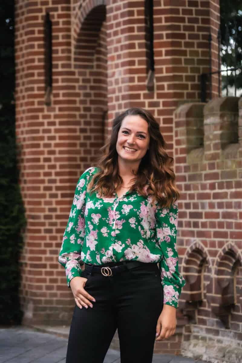 Dierenshop Sittard, vriendelijke medewerker in bloemrijke blouse voor dierenbenodigdheden.